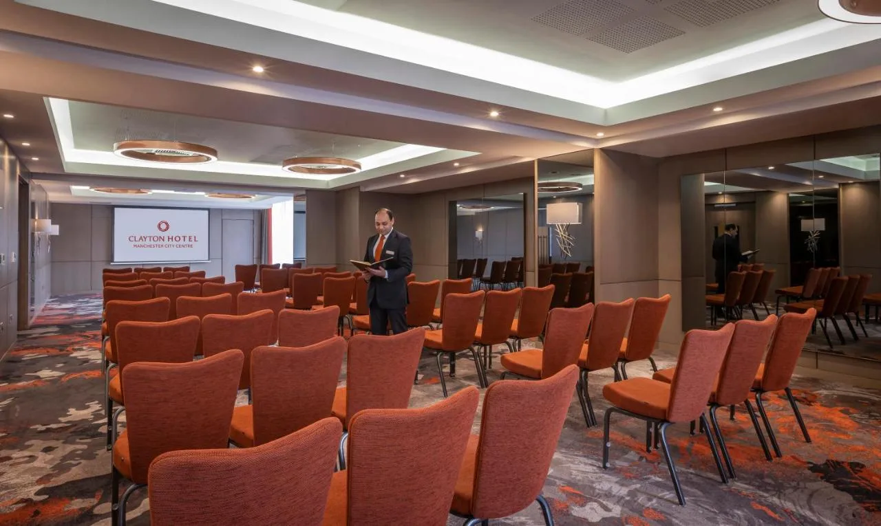 a man standing in front of a room with chairs at Clayton Hotel Manchester City Centre in Manchester